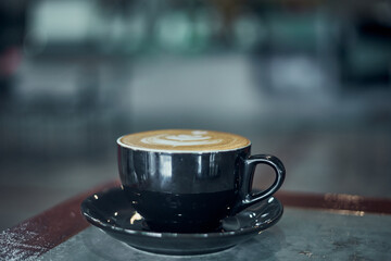 Hot cappuccino latte art in a Black ceramic cup on the table at coffee shop