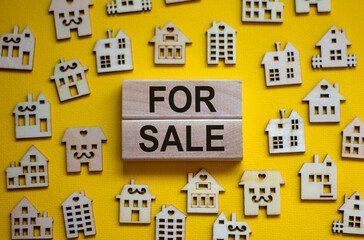 Wooden blocks form the words 'for sale', miniature wooden houses. Beautiful yellow background, copy space. Business concept.