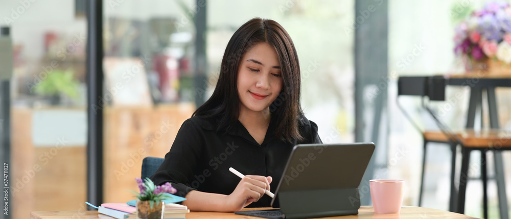 Aufkleber a woman is using a computer tablet with a keyboard case at the wooden working desk.