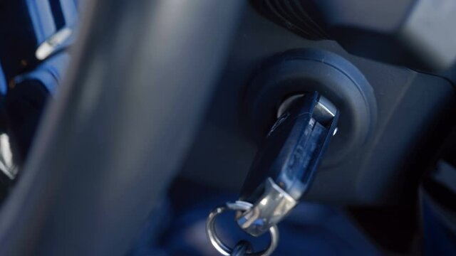 The driver inserts the ignition key into the ignition lock, turns it and starts the engine, then turns off the engine and removes the key. Closeup