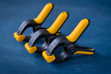 Three plastic spring clips on blue background, closeup, shallow depth of field