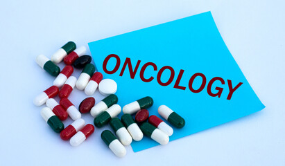 ONCOLOGY word on a blue sheet of paper against the background of multicolored tablets
