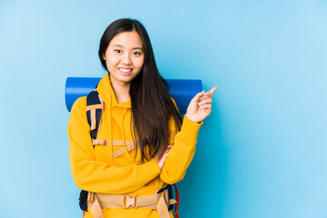 Young chinese backpacker woman isolated smiling cheerfully pointing with forefinger away.