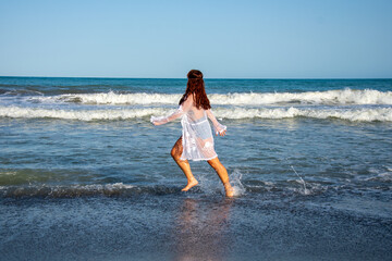 Fototapeta premium Young woman running through the coast of the beach 