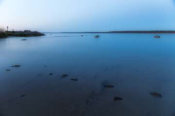 Sea shore and rocks at the sunset, cold blue sky. Nature composition.