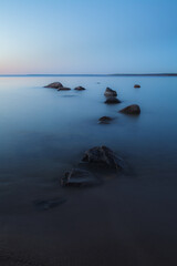 Sea shore and rocks at the sunset, cold blue sky. Nature composition.