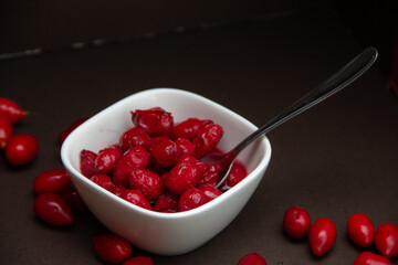 red dogwood berries and a bowl of jam on a dark background