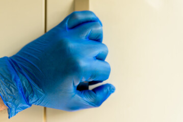 male hand in rubber gloves holding door handle during covid 19 lockdown
