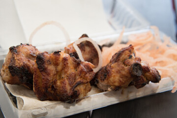 Grilled meat chunks on the fire close-up. The meat is lying on the pita bread in a plastic container. Pork or lamb.