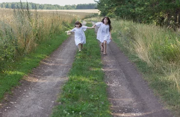 Poster Twee schattige kleine meisjes rennen op de weg. Fijne zomertijd. © Albert Ziganshin