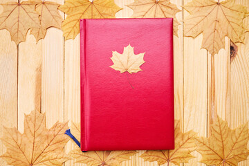 blank diary or book on a wooden desk. decorated with fall maple leaves. minimal composition. above...