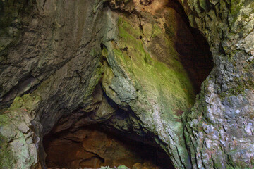 Inside view of moss covered cave cavities. Entrance to the copper cave in Santamaria de los...