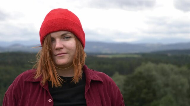 young girl in red hat without makeup looking in camera with mountains on background