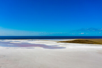 White lake, covered with salt, against the blue sea and sky. The view from the top.