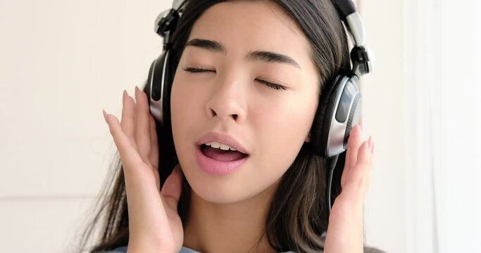 Happy woman listening and singing song using headphones