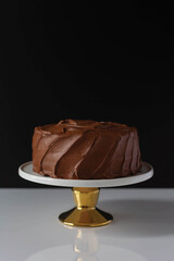 Chocolate cake on stand with black background and white counter