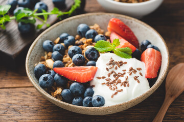 Healthy breakfast food with greek yogurt, crunchy oat granola and fruits on a wooden table. Sustainable eating