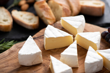 Sliced brie cheese or camembert on wooden board. Tasty french soft cheese