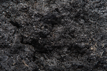 Blurred black background in soft focus with hard coal at high magnification. An image on the theme of geology and the extraction of minerals and natural fuels.