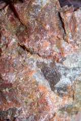 Photograph of a granite surface interspersed with transparent mica in soft focus at high magnification. Fine texture of natural mineral of pink color with blurred background.