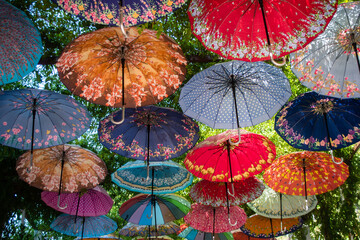 Fototapeta na wymiar Colorful umbrellas decorating the top of the street. The umbrella serves also as a shade and protection against the sunshine. 