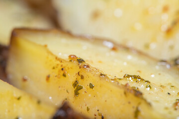 Background with slices of fried potatoes in oil and with greens on a metal baking sheet