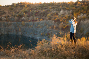 Autumn girl in blue sweater and hat standing backwards and admire nature lake view. Autumn forest colors with girl back view.
