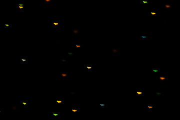 Halloween background. Defocused bokeh multicolor lights in shape of bats on black background.