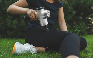 Woman massaging leg with massage percussion device after workout.
