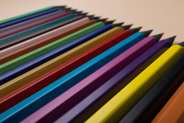 Fototapeta premium Row of color blackwood pencils on beige background. Education concept