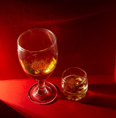 copa y vaso con ron servido en un bar elegante. Esta foto tiene un fondo rojo. Perfecto para las fiestas y reuniones familiares como la navidad, año nuevo o en una cita romántica 