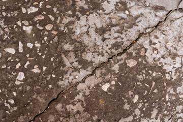Concrete slab, smoothed under the influence of rain, sun and wind, with a crack along which dry blades of grass. Narrow focus.