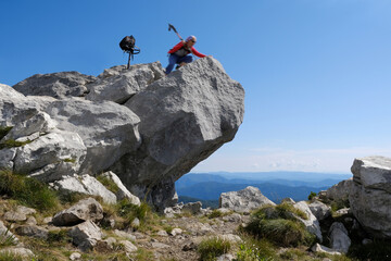 Mountain view with silhouette of woman tourist blurry in motion on huge rock on viewpoint in beautiful National Park Risnjak, Croatia