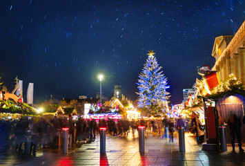 Fototapeta na wymiar Crowds over illuminated Christmas tree and market fair on Castle square or Schlossplatz in German, Stuttgart