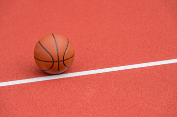 Orange basketball on brown court of gymnasium sport floor. Street basketball concept