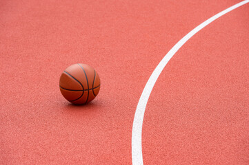 Orange basketball on brown court of gymnasium sport floor. Street basketball concept