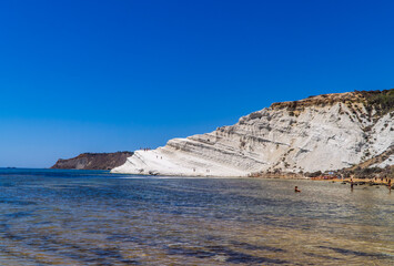 Fototapeta na wymiar Limestone white cliffs with beach and swimmers at the Scala dei Turchi (Stair of the Turks) near Realmonte, Sicily, Italy