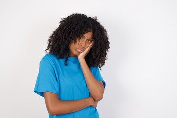 Very bored Young african woman with curly hair wearing casual blue shirt over white background...