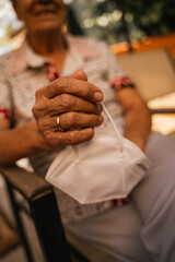 Spanish grandmother sitting with mask in hand and wedding ring