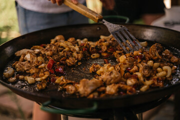 Young Spanish woman moving the garnish of typical Spanish paella with spatula