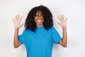 Young african woman with curly hair wearing casual blue shirt over white background showing and pointing up with fingers number ten while smiling confident and happy.