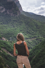 Naklejka na ściany i meble Blonde girl looks at a beautiful gorge in kabardino-balkaria republic.