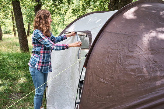 Woman setting up camping tent at forest