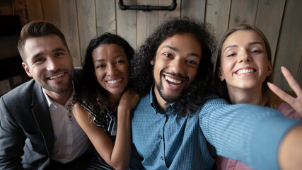 Head shot portrait smiling overjoyed diverse people taking selfie together, excited happy friends posing for funny photo in cafe, looking at camera, hugging and laughing, gathering on weekend