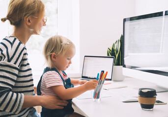 Mother working from home with little child.