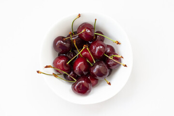 red cherries in a white bowl on the white background, isolated