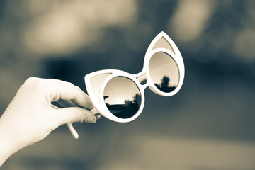 Cat eye sunglasses hold by hand shoot outside closeup. Selective focus 