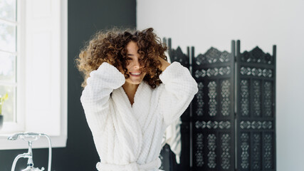 Young adult afro american woman in bathrobe spending morning in bathroom
