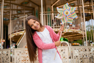 Cute teen girl plays near carousel in toy breeze