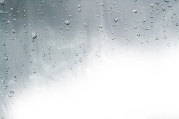 Raindrops on window glasses surface with cloudy background .